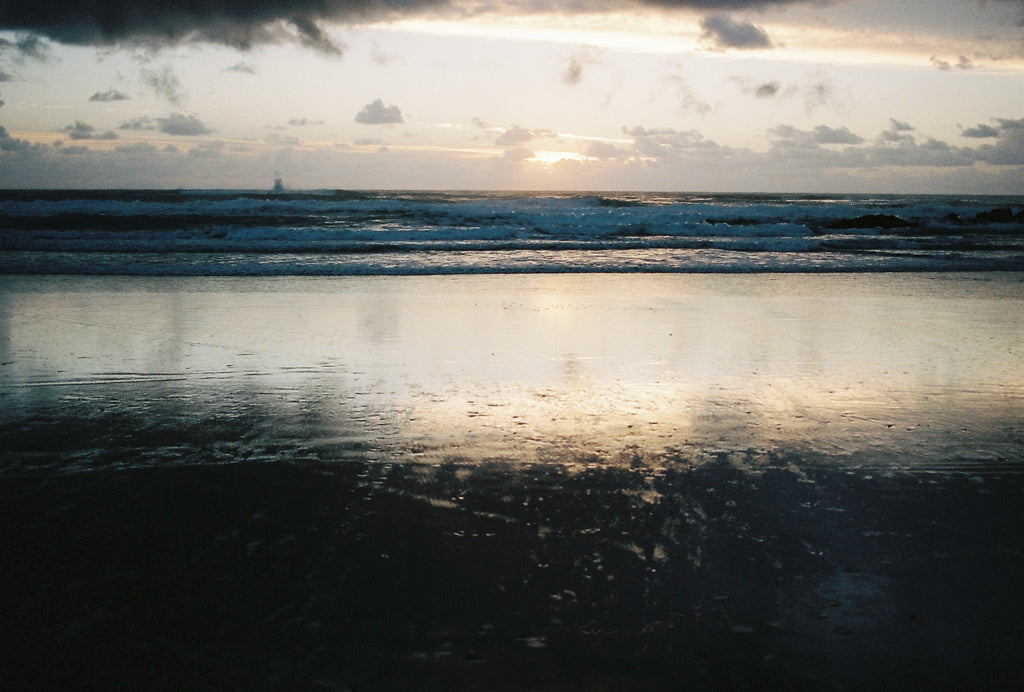 Byron bay beach, dark skies, reflections of water in the sand.