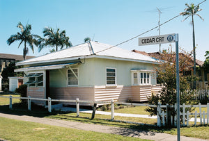 A 1950's beach house painted pink & white with a tin roof, retro style windows located on the Gold Coast of Queensland Australia. The sky is blue & there are tall palm trees. Artwork Prints, wall art, GoldCoast Queensland, Australia, Photographic prints, Ocean, Beach, Framed artwork, Beach Posters, Australian Photography, Photography for sale, Film photography ,Vintage photo style Interior design, Film photography, Pictures, sun, surf , wall art, prints for sale, architecture,