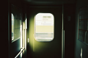 A photograph of the inside doorway in a fast moving train to Osaka Japan. The doorway is green.