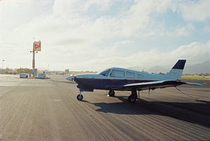 A vintege 1970's single engine plane sits on an empty tamrac in the Sanra Ynez countryside in California.