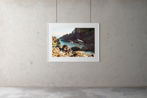 Two young girls walk into the water around the rocks to go surfing. They are wearing bathers and carry surfboards. blue water looks warm.  calm water, blue sky, the pass, byron bay, surfing, surf photography, Artwork Prints, wall art,  Photographic prints,  Framed artwork,  Australian  Photography, wall art, beach prints, coastal prints, ocean prints,  Film photography, Vintage photo, style  Interior design, Pictures Abstract film photography, photography art, Australia, sun, beach,