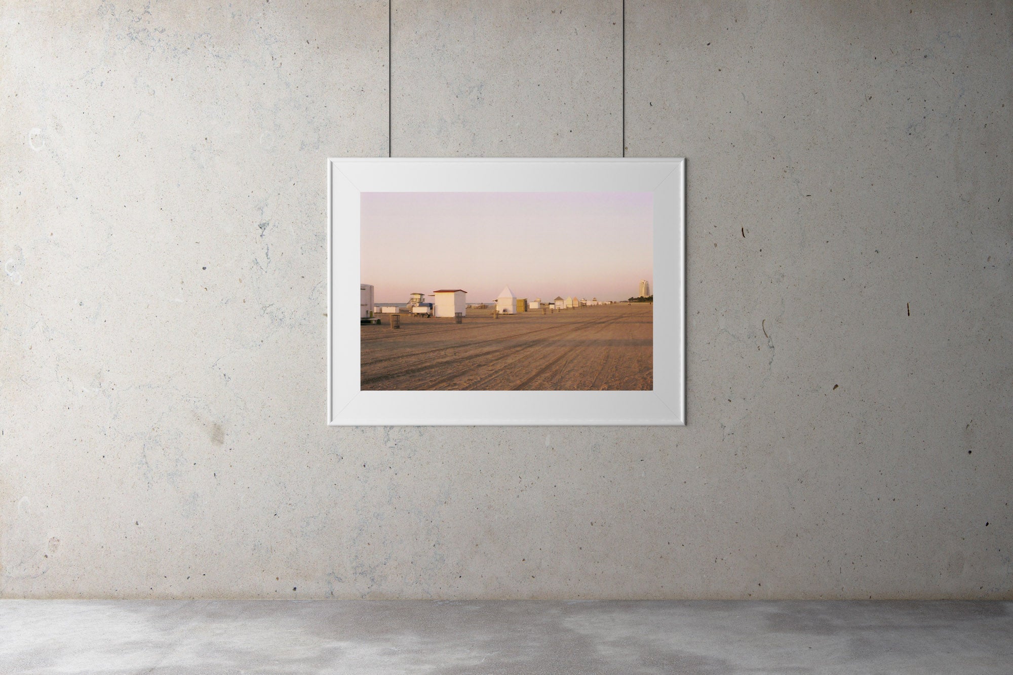 A photograph of an empty beach in Miami Florida. There are white beach boxes in the sand & the water is in the background.