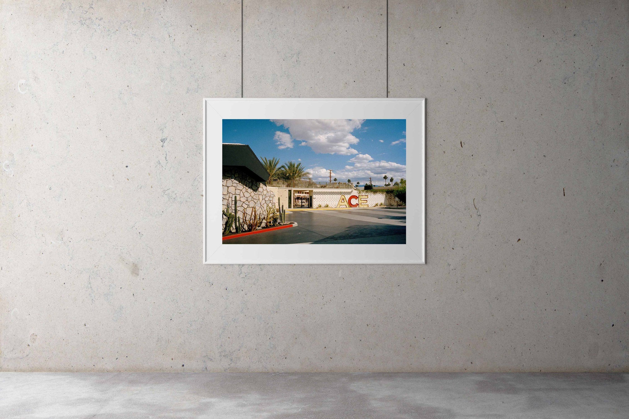 A photograph of the outside of the Ace Hotel in Palm Springs California. There is a large mid century sign that says ACE Blue skies & clouds with palm trees in the background. USA, Artwork, Prints, wall art, California, Photographic prints, Ocean Palm Springs, Framed artwork, Photography,  Film photography, Vintage photo style,  Interior design, beach, buy Art, photography art, buy art, ace hotel, Prints for sale, art prints, colour photography, sun, beach, sun baking, retro, interior design artwork,