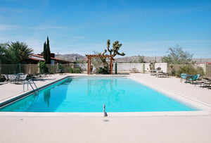 The empty 1970's Joshua Tree swimming pool in the desert, with cactus &old 1970's furniture