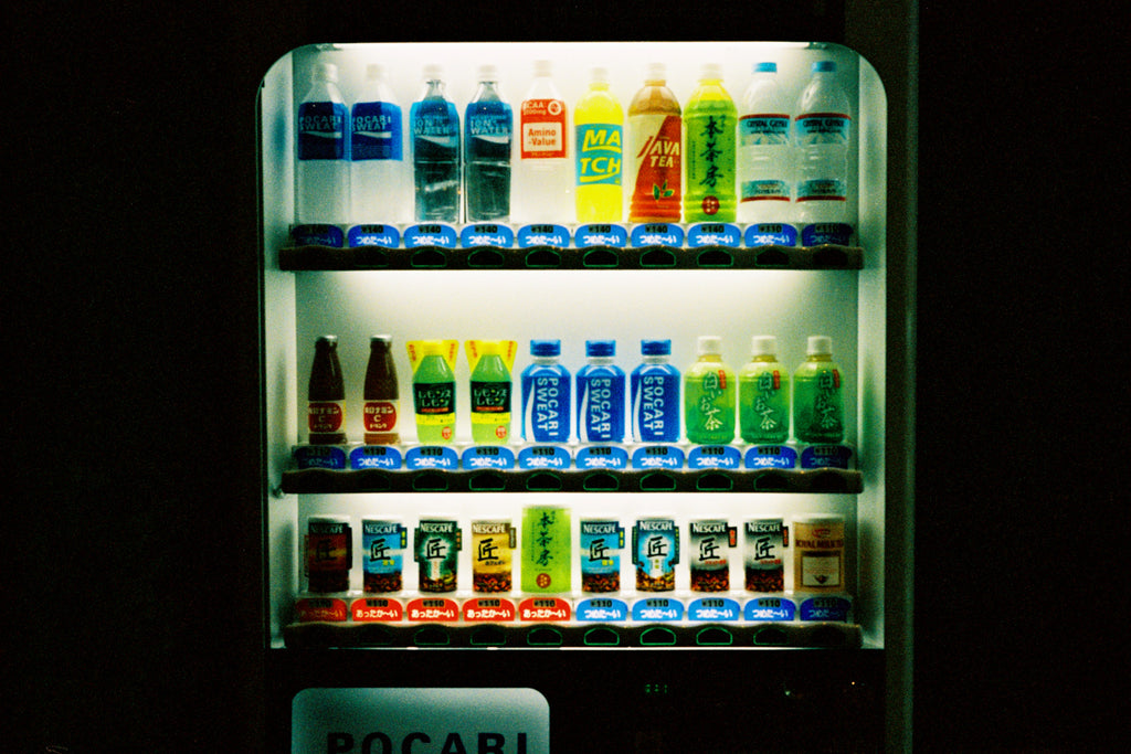 A Japanese vending machine with bright bottles & black borders.  Tokyo Japan. 