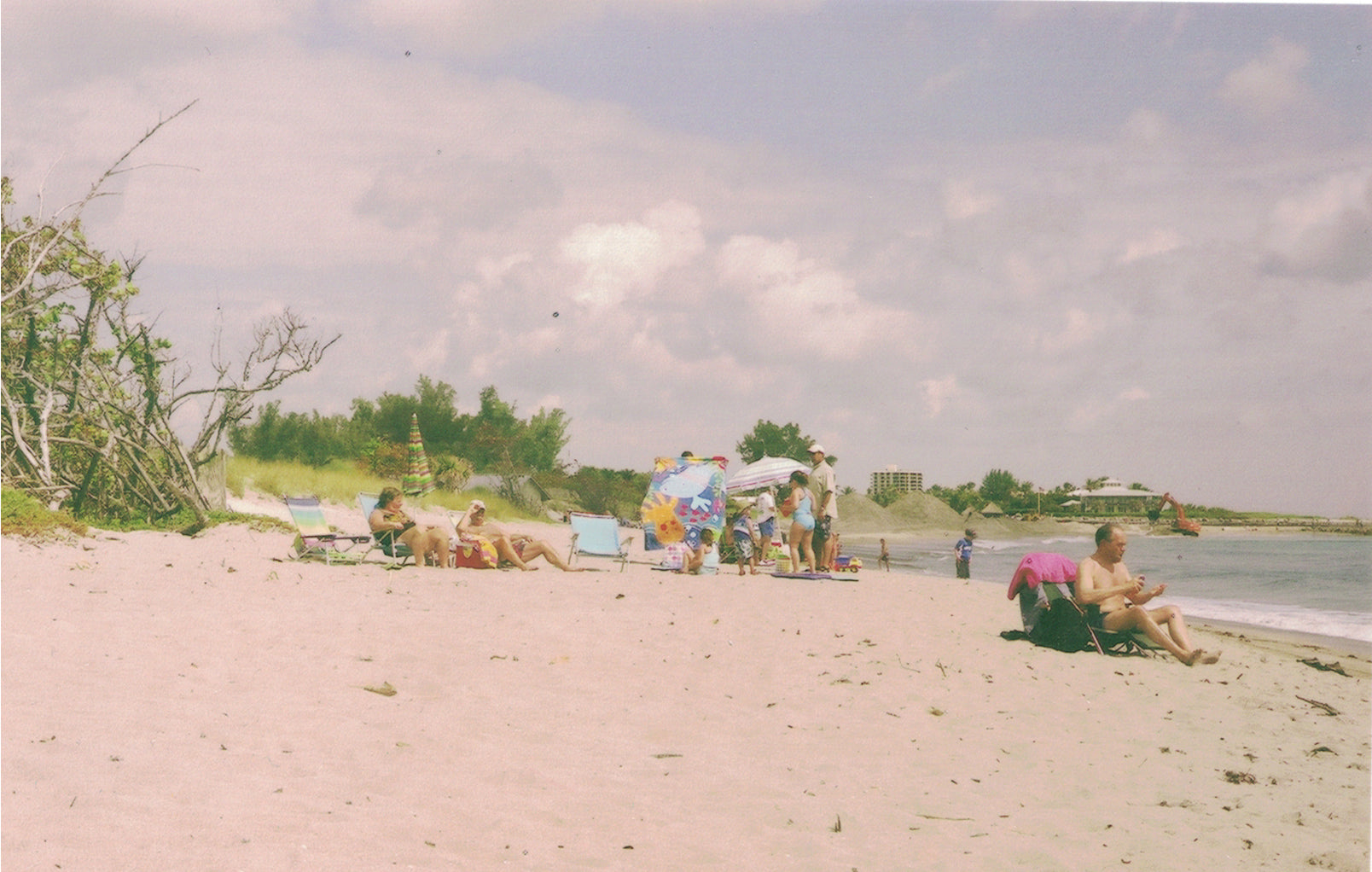 Miami Beach in the morning, people sit on ther beach under umbrella's, sand & blue calm water.